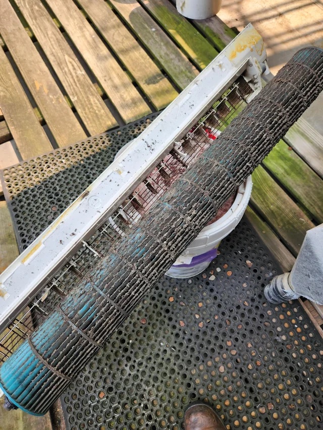 A mini-split blower wheel removed from the unit, its blades completely caked in grey felted dust